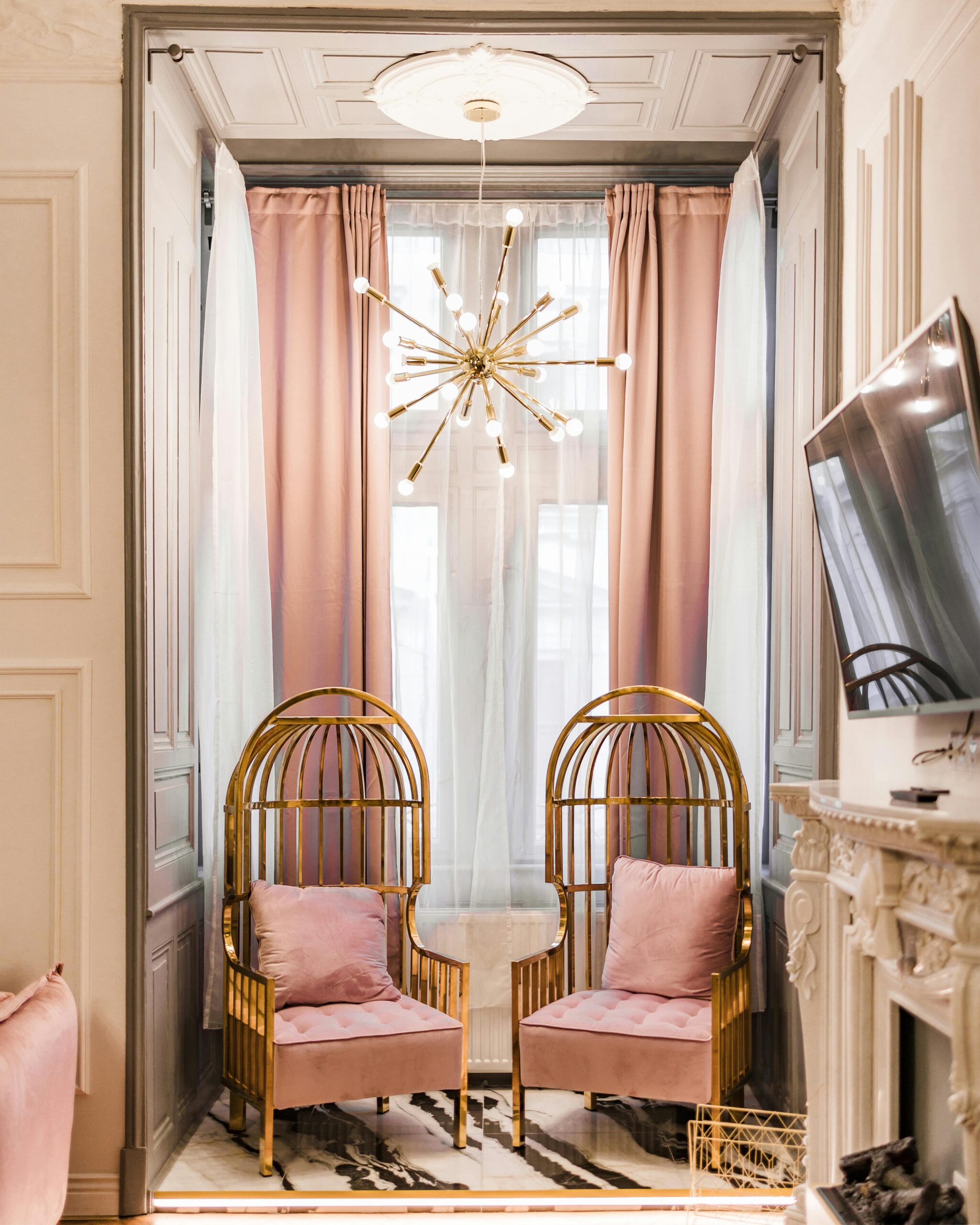 Elegant living space featuring pink velvet chairs and gold accents in a modern classic interior.